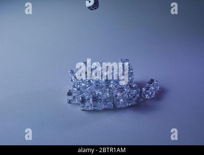 Set of ice cubes and dice falling on them, gray background, chaos Stock Photo
