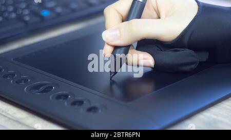 Designer Illustrator draws comics, sketches. Freelance. A woman's hand in a special glove draws on a graphic tablet. Digital tablet, visual, multimedi Stock Photo