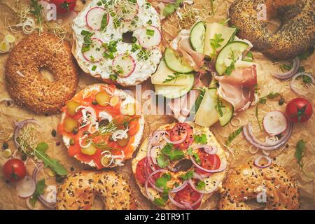 Tasty colorful various bagels with healthy ingredients served on brown baking paper Stock Photo