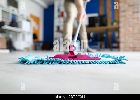 Male hand hold blue plastic mop against modern office closeup Stock Photo