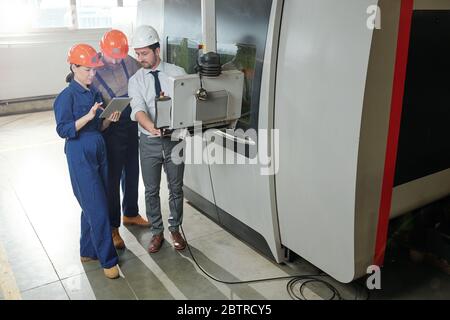 Engineers and programmer working with modern automated CNC machine in workshop Stock Photo