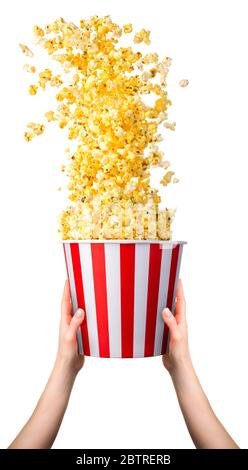 Woman hand holding striped bucket with flying popcorn isolated on white Stock Photo