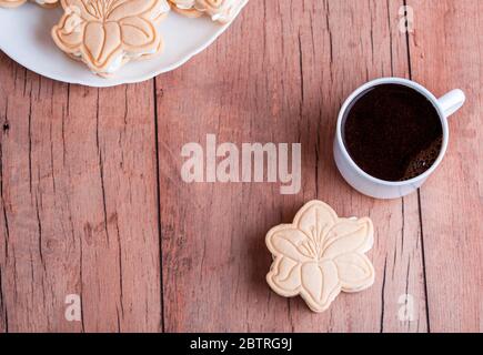 Shortbread cookies with meringue in the form of a flower, on a light wood background. Fragrant coffee Stock Photo