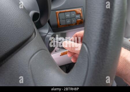 Closeup POV shot through the steering wheel of a vehicle, to a man’s hand turning the key in the ignition. Stock Photo