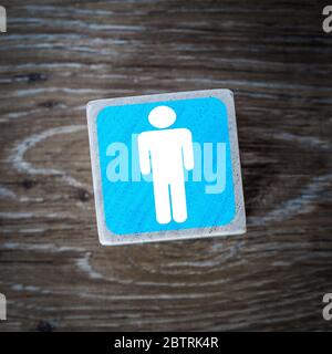 A blue men's toilet sign, symbol or icon on a wooden block with a wood background and copy space Stock Photo