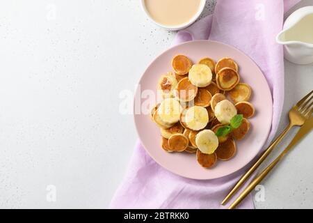Homemade tiny cerel pancakes with banana on white table. View from above. Copy space. Stock Photo