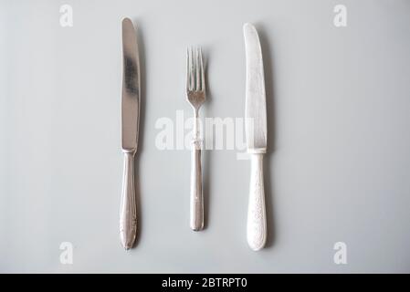 Silverware, old used silver knifes and fork on gray surface, top view Stock Photo