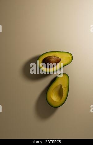 Two halves of avocado fruit with kernel on a light background. top view Stock Photo