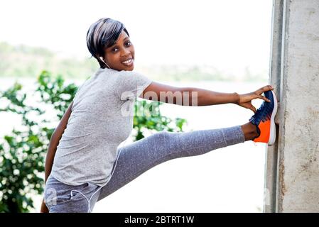 Sport and recreation.Small woman in gray sportswear stretching outdoors. Stock Photo