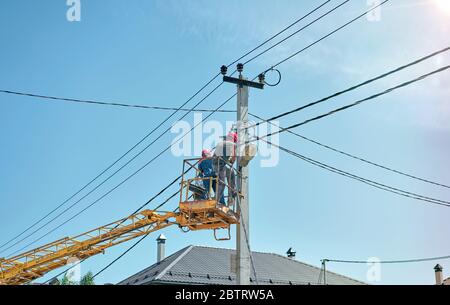 electrician in a car tower to repair power lines Stock Photo