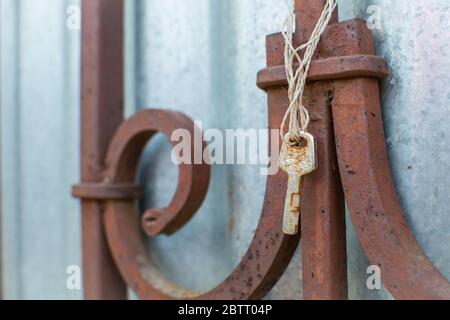 Old rusty key hangs on the old fence. Lost keys and opportunities concept. Close up with copy space for text. Stock Photo