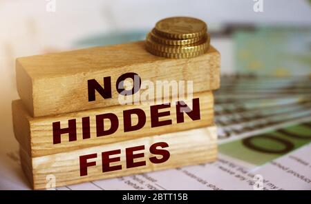 No hidden fees word written on wooden block, 100 Euro currency bills and coins. Financial agreement concept. Selective focus Stock Photo