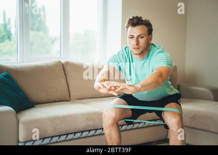 Caucasian man with blonde hair warming up with elastic bands before doing morning exercises Stock Photo