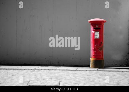 King George V Red post box at the Shambles on the Piazza, in Huddersfield Town with desaturated black and white background to highlight the red box Stock Photo