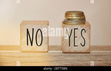 Words NO and YES on wooden cubes woth coins put on yes cube. Business or personal desicion making concept Stock Photo