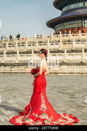 Beijing / China - April 5, 2015: Pretty Chinese girl in red wedding dress, posing in front of the Temple of Heaven in Beijing, China Stock Photo