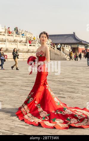 Beijing / China - April 5, 2015: Pretty Chinese girl in red wedding dress, posing in front of the Temple of Heaven in Beijing, China Stock Photo