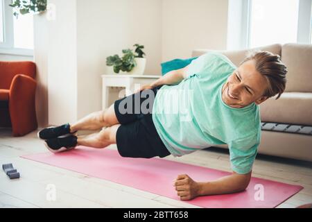 Blonde caucasian man smiling while making exercises on a yoga carpet at home Stock Photo