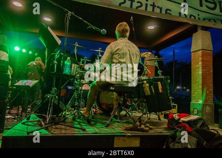 Rock band on stage, in concert, singer, bass guitar, lead guitar and drums,  shot from behind. Stock Photo
