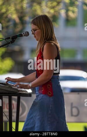 Attractive female, in outdoor concert, singing and playing keyboards. Stock Photo