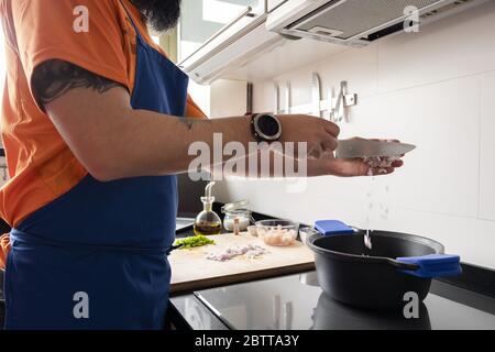 unrecognizable man putting chopped onions in a pot to prepare a healthy meal, home cooking concept Stock Photo