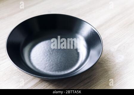 empty black plate on a white wooden table, food concept Stock Photo