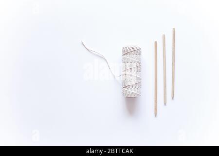 Tools and materials for macrame weaving over white surface. Cotton ropes and sticks from the river, grinded by water. Flat lay, top view. space for te Stock Photo