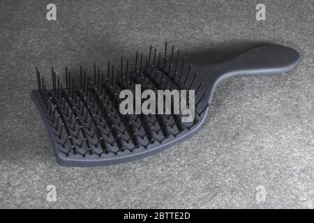 Black plastic massage comb on a dark gray background. Stock Photo