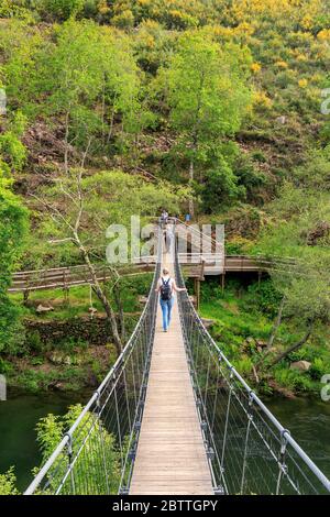 Arouca, Portugal - April 28, 2019: Suspended pedestrian bridge over the Paiva river, giving access to the Paiva walkways with people to cross. Stock Photo