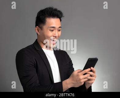 Surprised young business man watching the mobile phone Stock Photo
