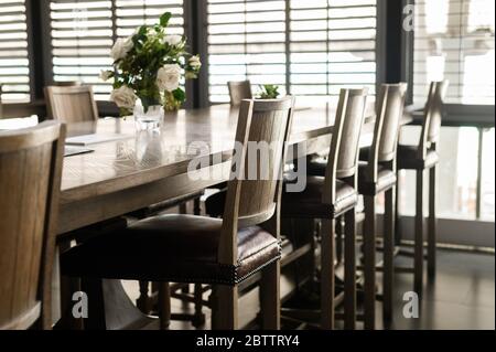 Empty wooden chairs with leather padding are set around tables in restaurant Stock Photo