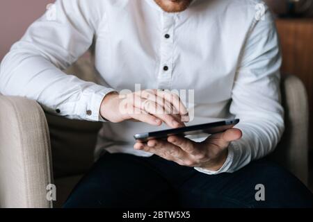 Close-up of a businessman in white stylish shirt working on digital tablet Stock Photo
