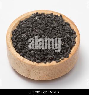Close-up view of raw black cumins in a small wooden bowl on white background.