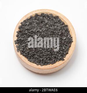 Close-up view of raw black cumins in a small wooden bowl on white background.