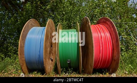 Empty pipes for road construction on the roadside. Big blue red and green spool in Germany. Stock Photo