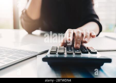 Close up Business woman using calculator and laptop for do math finance Stock Photo