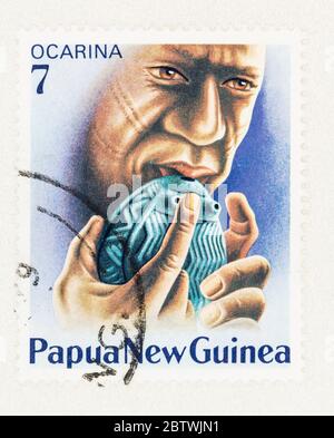 SEATTLE WASHINGTON - May 25, 2020:  Man playing native wind instrument, Ocarina, on 1979 Papua New Guinea postage stamp. Scott # 491 Stock Photo