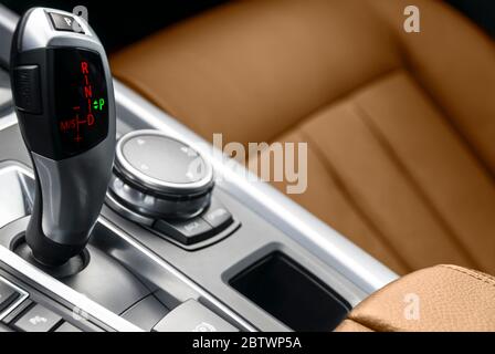 Automatic gear stick transmission of a modern car. Multimedia and navigation control buttons. Car interior details. Transmission shift. Brown leather Stock Photo