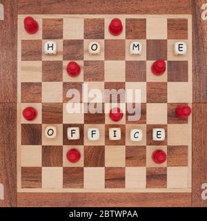 Red pawns work from home on a small chessboard and keep their distance Stock Photo