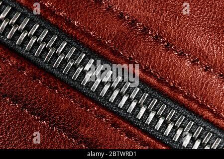 Macro shot of zipper on red leather texture background with stitching. Horizontal background from a close-up of red leather material Stock Photo