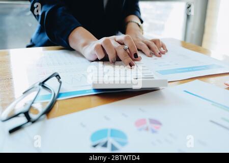 Close up Businesswoman using calculator and laptop for do math finance on wooden desk in office Stock Photo