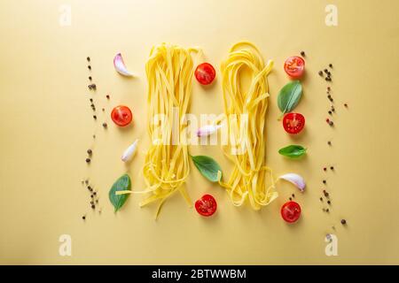 Overhead view of Homemade pasta and cherry tomatoes on yellow surface Stock Photo