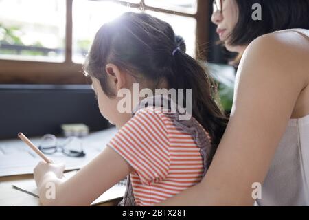 Businesswoman mother woman with a child girl working on the desk in the home, Quarantine isolation during the Coronavirus (COVID-19) health crisis Stock Photo