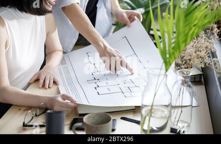 Young man and young woman architecture freelance looking at the blueprint working from home lifestyle in modern home office, Quarantine isolation duri Stock Photo