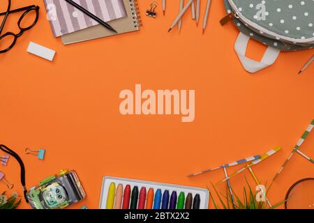Creative flatlay of education orange table with backpack, student books, camera, colorful crayon, eye glasses, empty space isolated on orange backgrou Stock Photo
