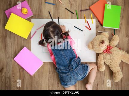 Adorable little girl drawing artwork. Studio shot top view of child on floor Stock Photo