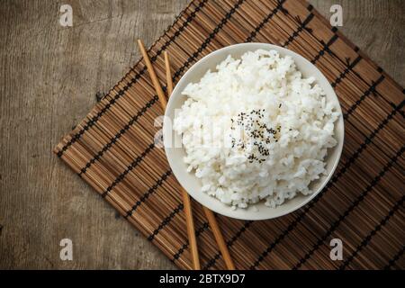 Steamed rice and black sesame seeds with chopsticks on a bamboo mat Stock Photo