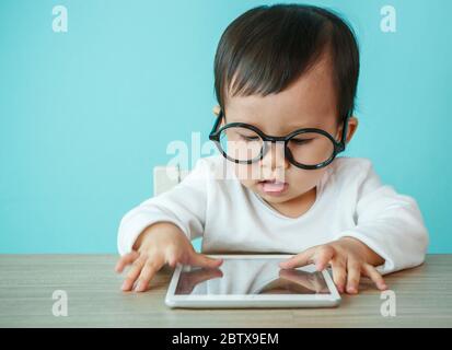 little baby on tablet pc on the blue background Stock Photo