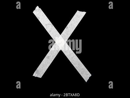 White cross by adhesive tape on black background Stock Photo