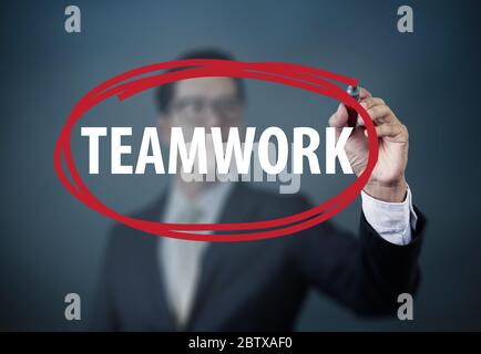 Businessman hand writing "Teamwork" with red marker on transparent board, new business concept, studio  shot Stock Photo